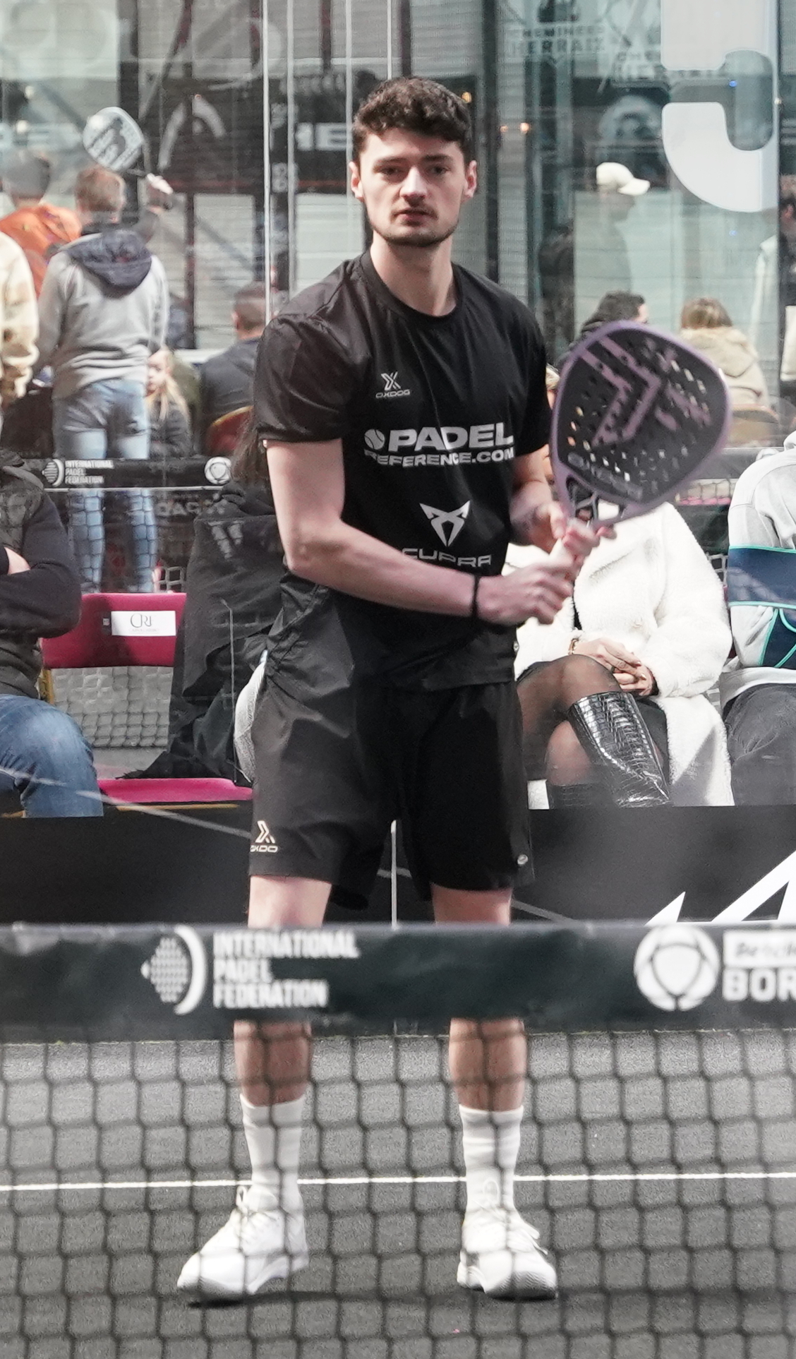 Coach in branded shirt carrying a padel racket bag